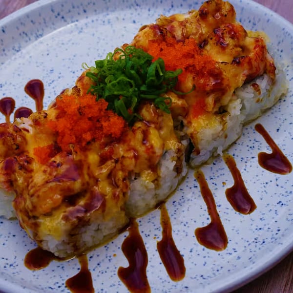 Yanagi Kitchen's baked sushi roll, topped with bright orange roe, green onions, and drizzled sauce.