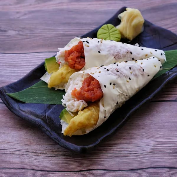 Two Yanagi Kitchen sushi hand rolls with tuna, avocado, and tempura, served with ginger and wasabi.
