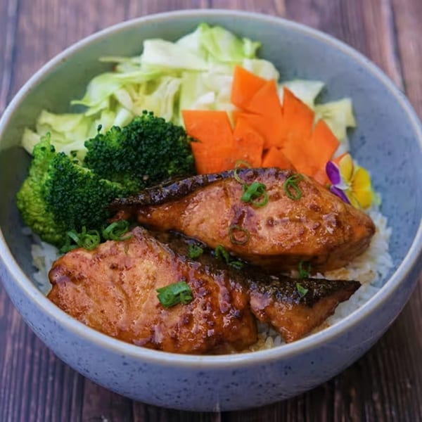 Yanagi Kitchen's teriyaki salmon bowl with rice, broccoli, shredded cabbage, and carved carrots.
