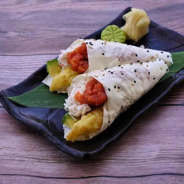 Two Yanagi Kitchen sushi hand rolls with tuna, avocado, and tempura, served with ginger and wasabi.
