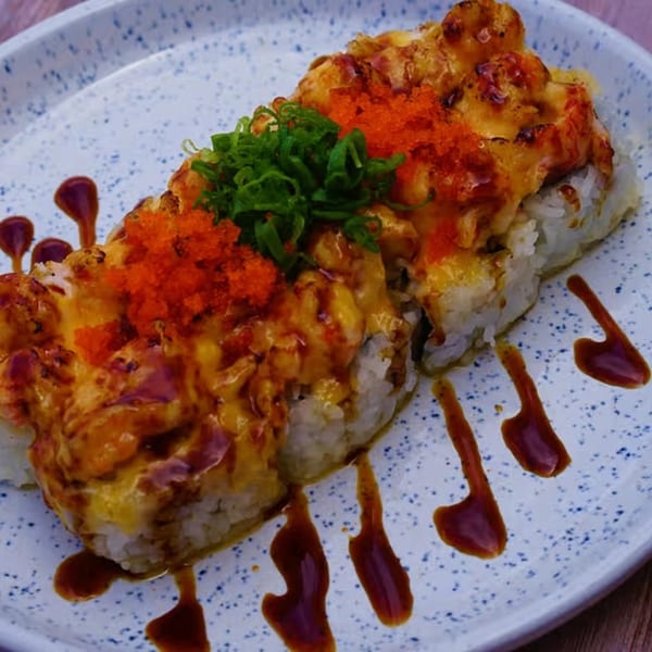 Yanagi Kitchen's baked sushi roll, topped with bright orange roe, green onions, and drizzled sauce.